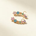 Gold-tone ear climber earrings with six graduated pastel pink, blue, mint and lilac crystals on ivory background