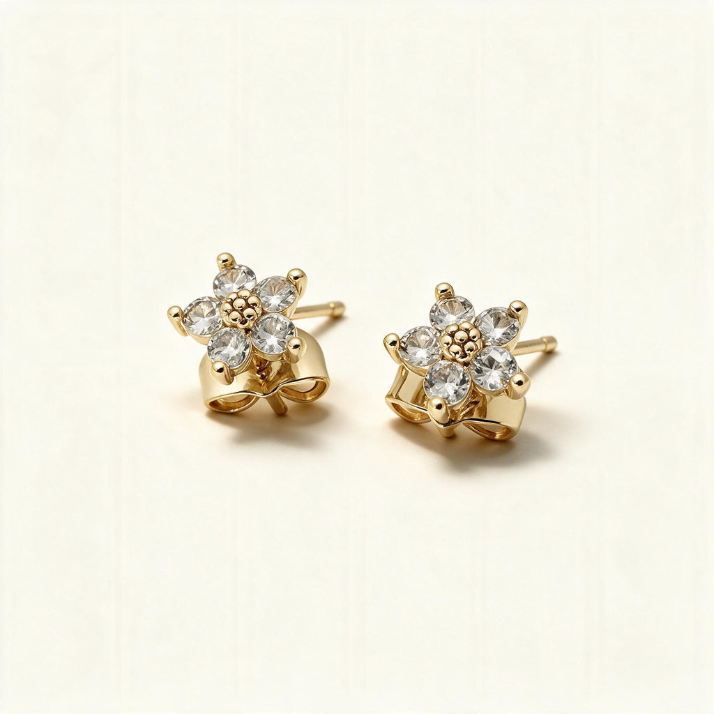 Gold-tone flower stud earrings with five cubic zirconia petals on ivory background