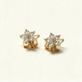 Gold-tone flower stud earrings with five cubic zirconia petals on ivory background