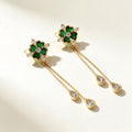 Gold-tone drop earrings with a green heart-petal clover top and two chains ending in clear teardrops