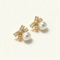 Gold-tone stud earrings with baguette crystal bow motif and large round shell pearl