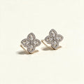 Silver-tone four-petal flower stud earrings outlined in cubic zirconia pave with pear-cut centres on ivory background