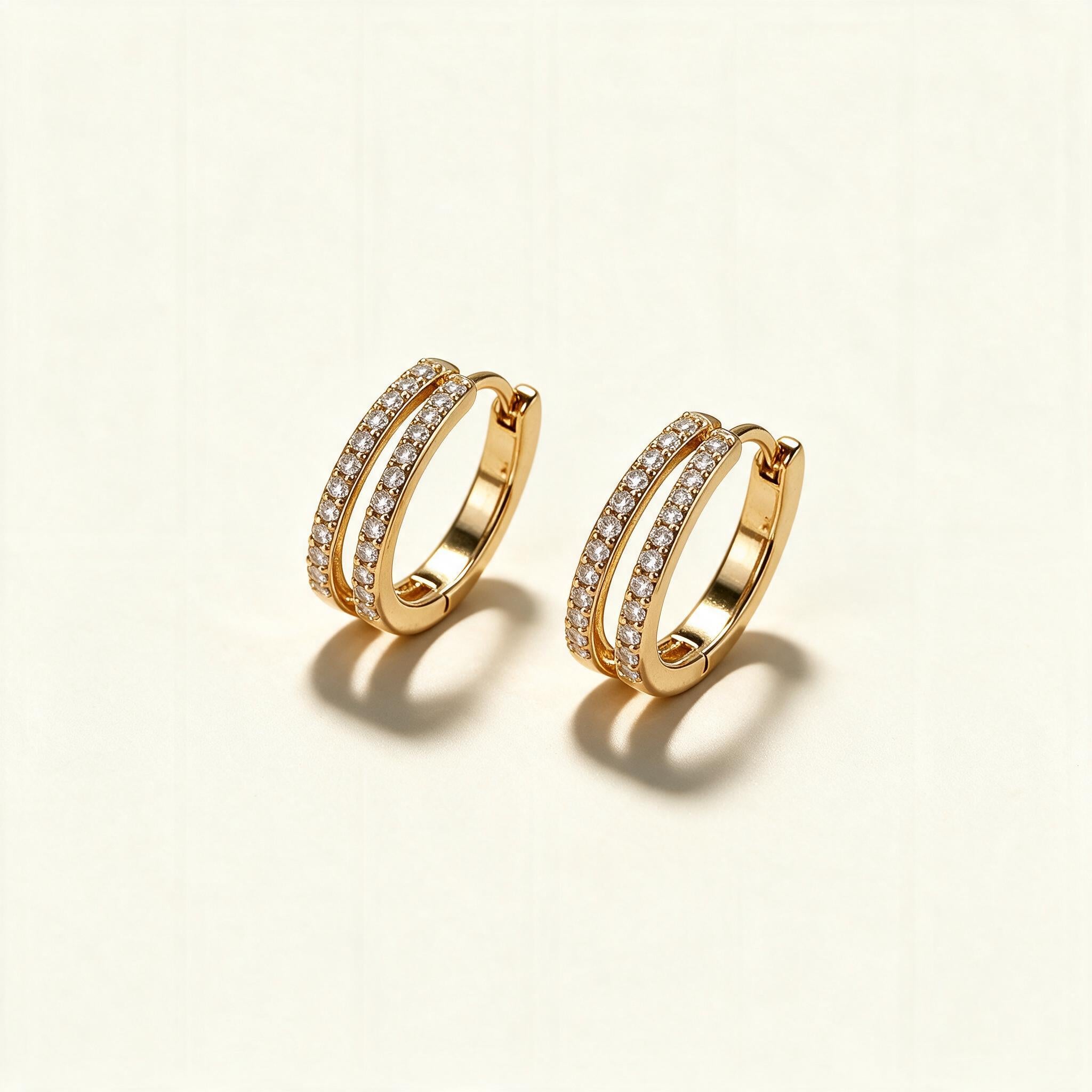 Gold-tone huggie hoop earrings with two rows of clear cubic zirconia pave on ivory background