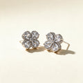 Silver-tone stud earrings with four large pear-cut clear crystals and a pave-set scalloped frame on ivory background