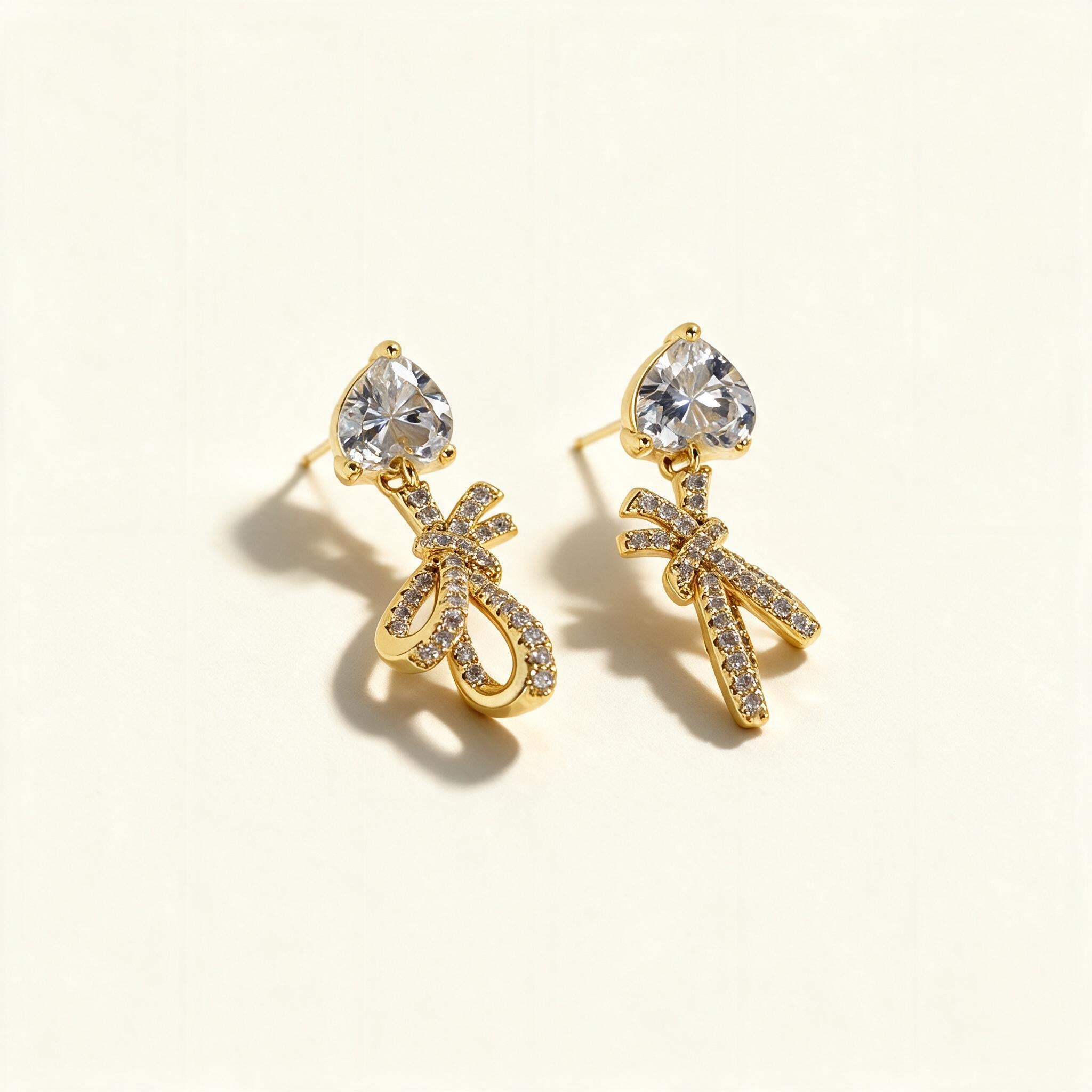 Gold-tone drop earrings with heart-cut cubic zirconia studs and pave crystal bow charms