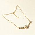 Gold-tone fine chain necklace with crystal flower and green leaf accents
