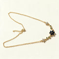 Gold-tone chain necklace with navy blue enamel flower and green leaf accents
