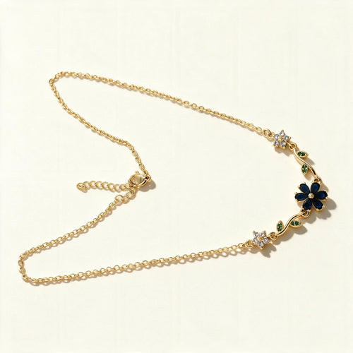 Gold-tone chain necklace with navy blue enamel flower and green leaf accents