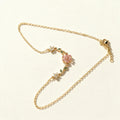 Gold-tone chain necklace with frosted pink flower and green leaf accents