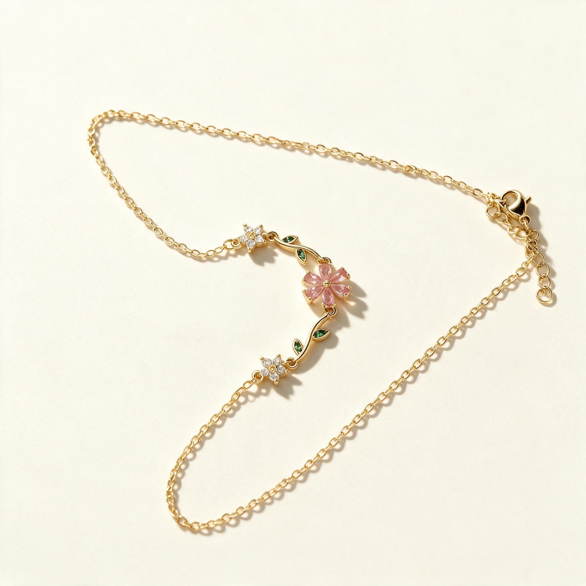Gold-tone chain necklace with frosted pink flower and green leaf accents