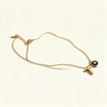 Gold-tone fine chain necklace with black enamel evil eye charm and initial letter
