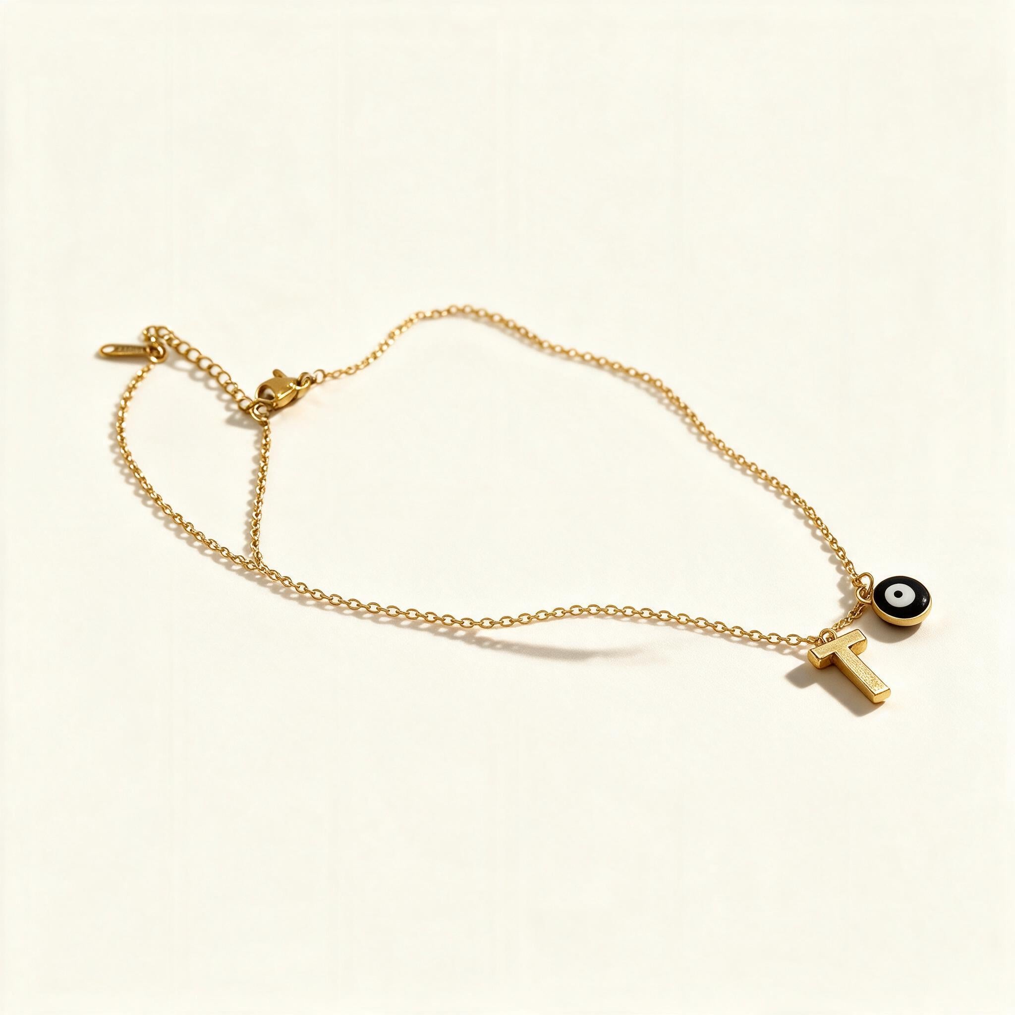 Gold-tone fine chain necklace with black enamel evil eye charm and initial letter