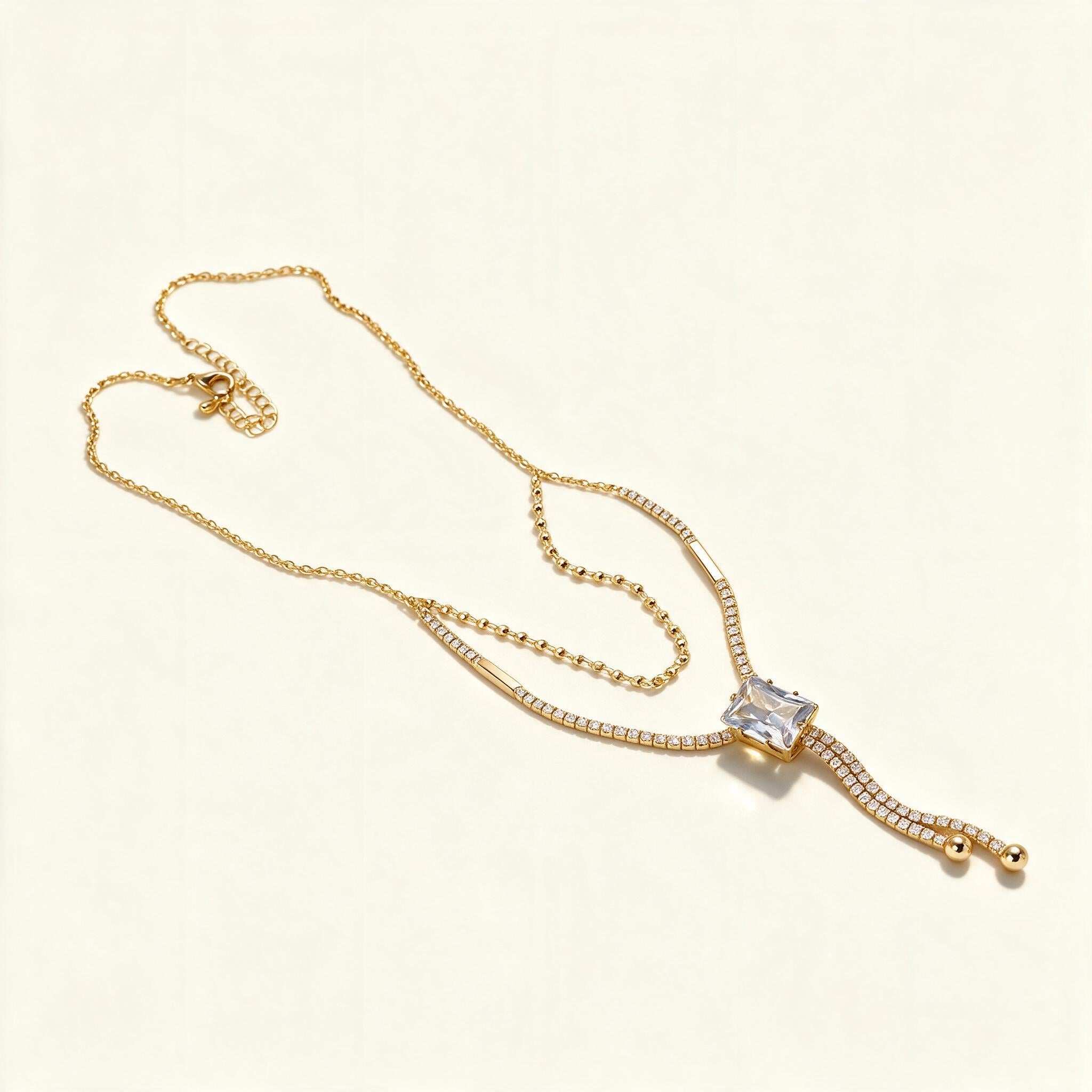 Gold-tone cubic zirconia tennis chain necklace with emerald-cut stone and slider drop