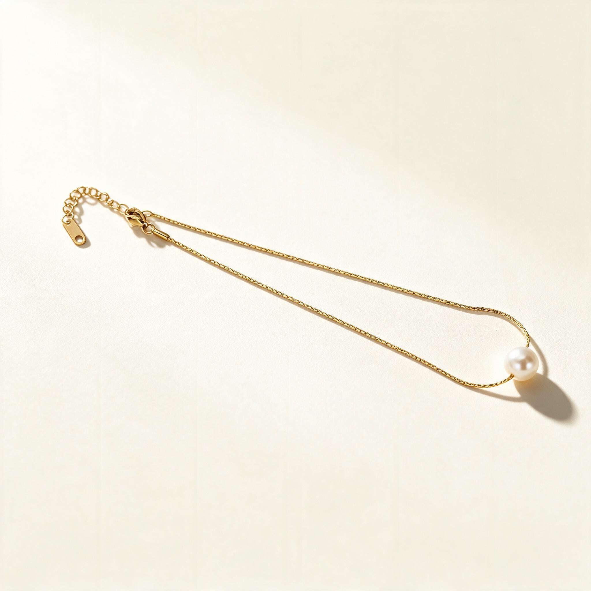 Gold-tone extra fine chain necklace with a single cream pearl