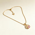 Gold-tone snake chain necklace with pink teardrop stone in a cubic zirconia halo