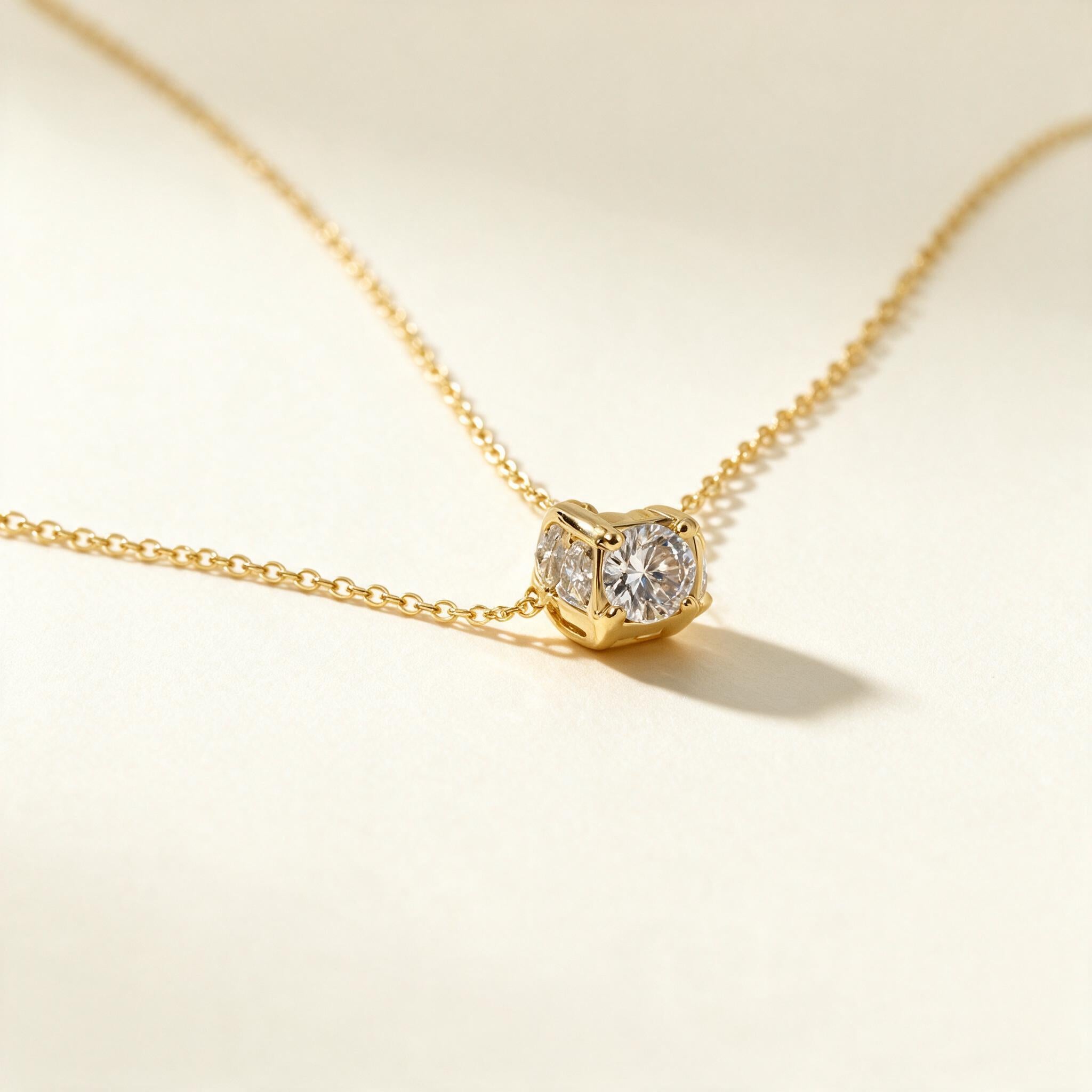 Gold-tone fine chain necklace with a single round cubic zirconia solitaire slider pendant on ivory background