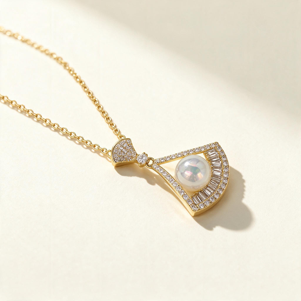 Gold-tone fan pendant necklace with a white shell pearl framed by baguette crystals