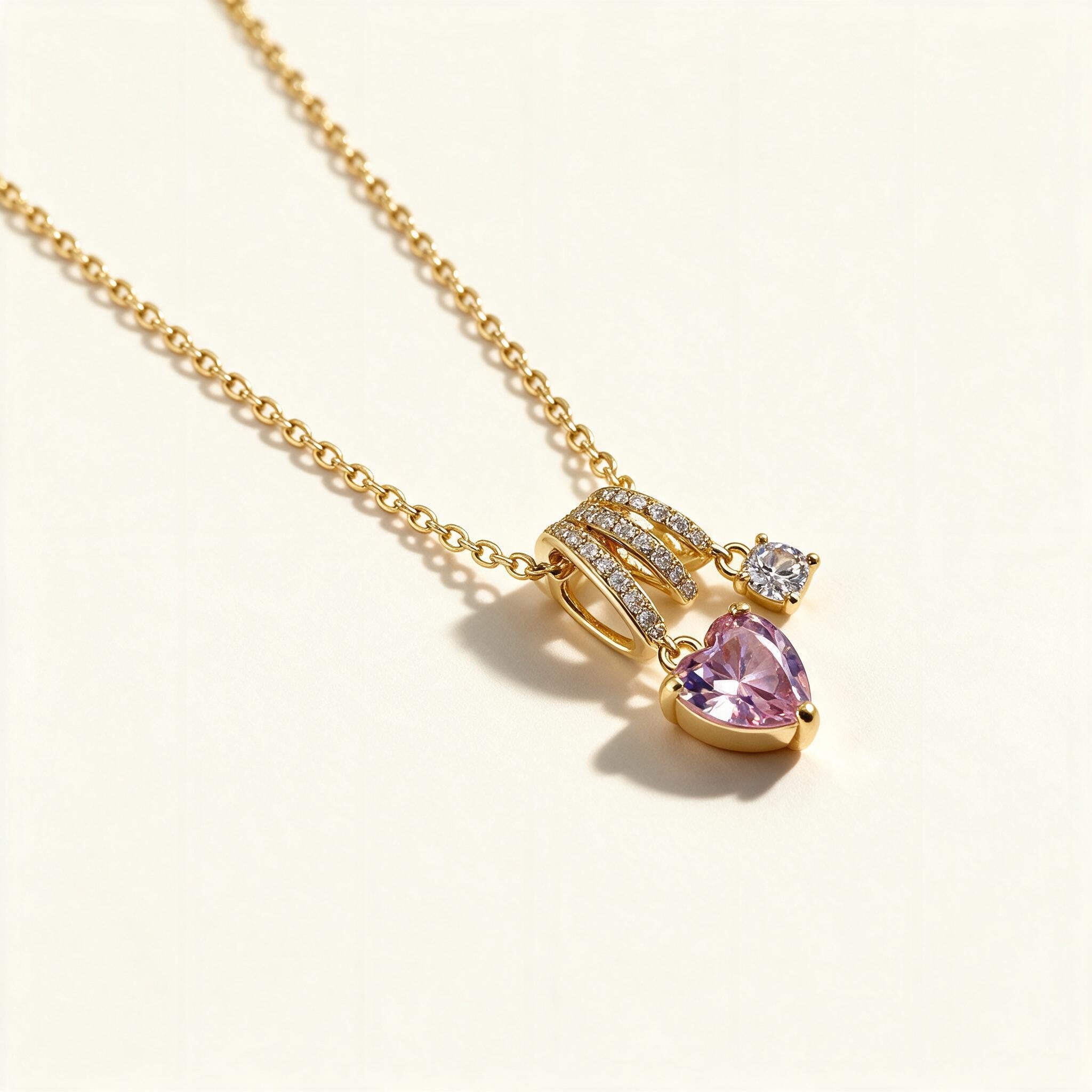 Gold-tone necklace with pink heart crystal pendant and pave triple-arc bail on a fine chain