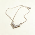 Silver-tone fine chain necklace with a curved fan of tapered baguette cubic zirconia stones on ivory background