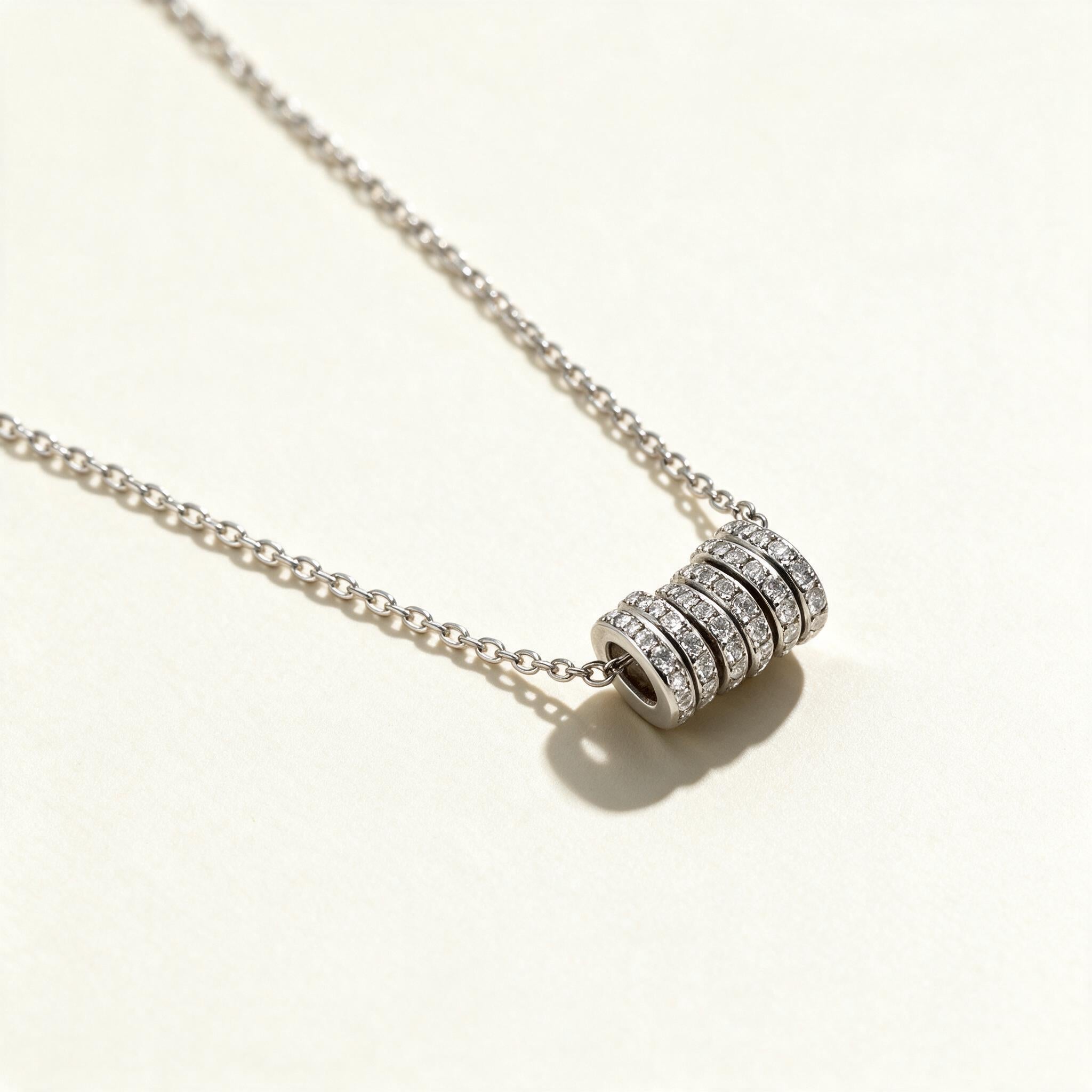 Silver-tone fine chain necklace with a cubic zirconia pave barrel pendant on ivory background