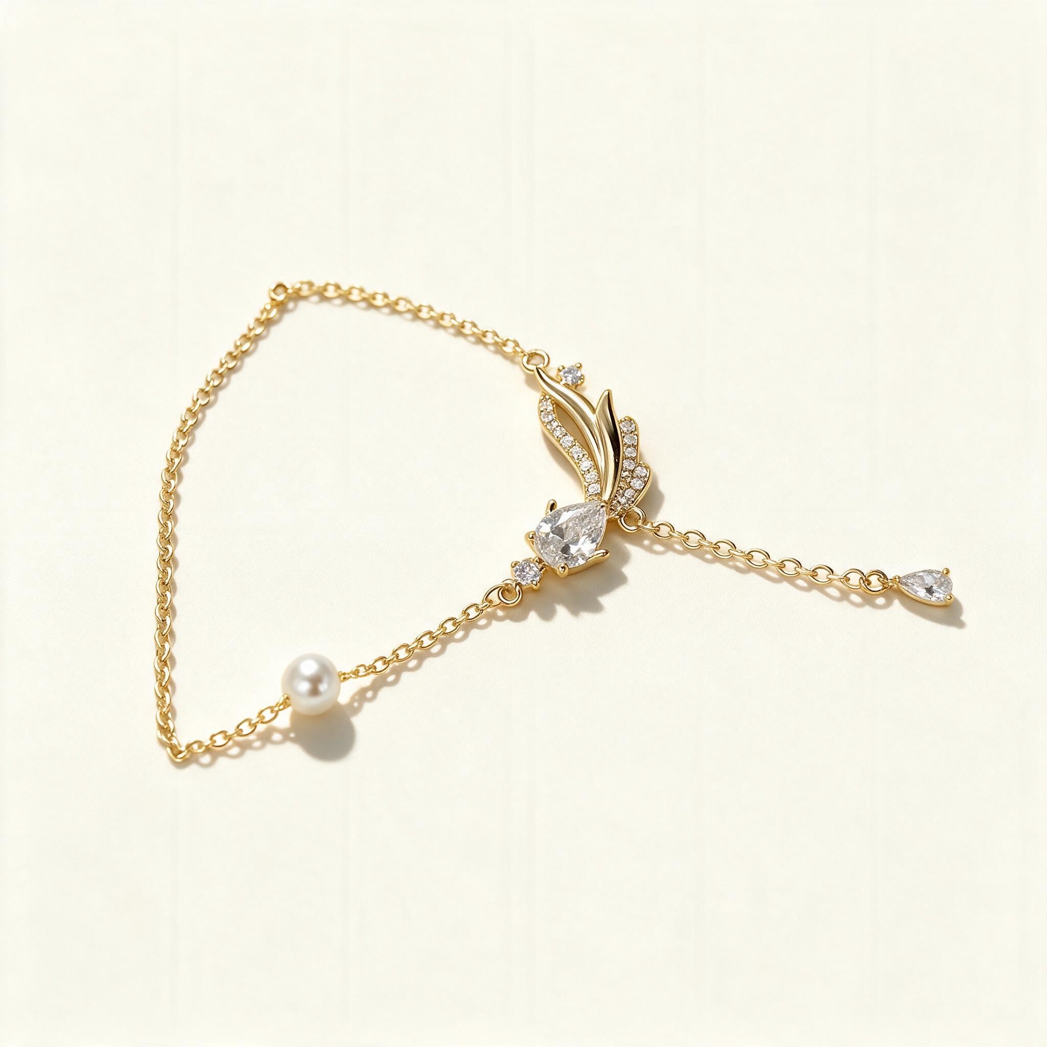 Gold-tone fine chain necklace with a pave leaf and pear-cut crystal pendant, a shell pearl station and a crystal drop on the extender