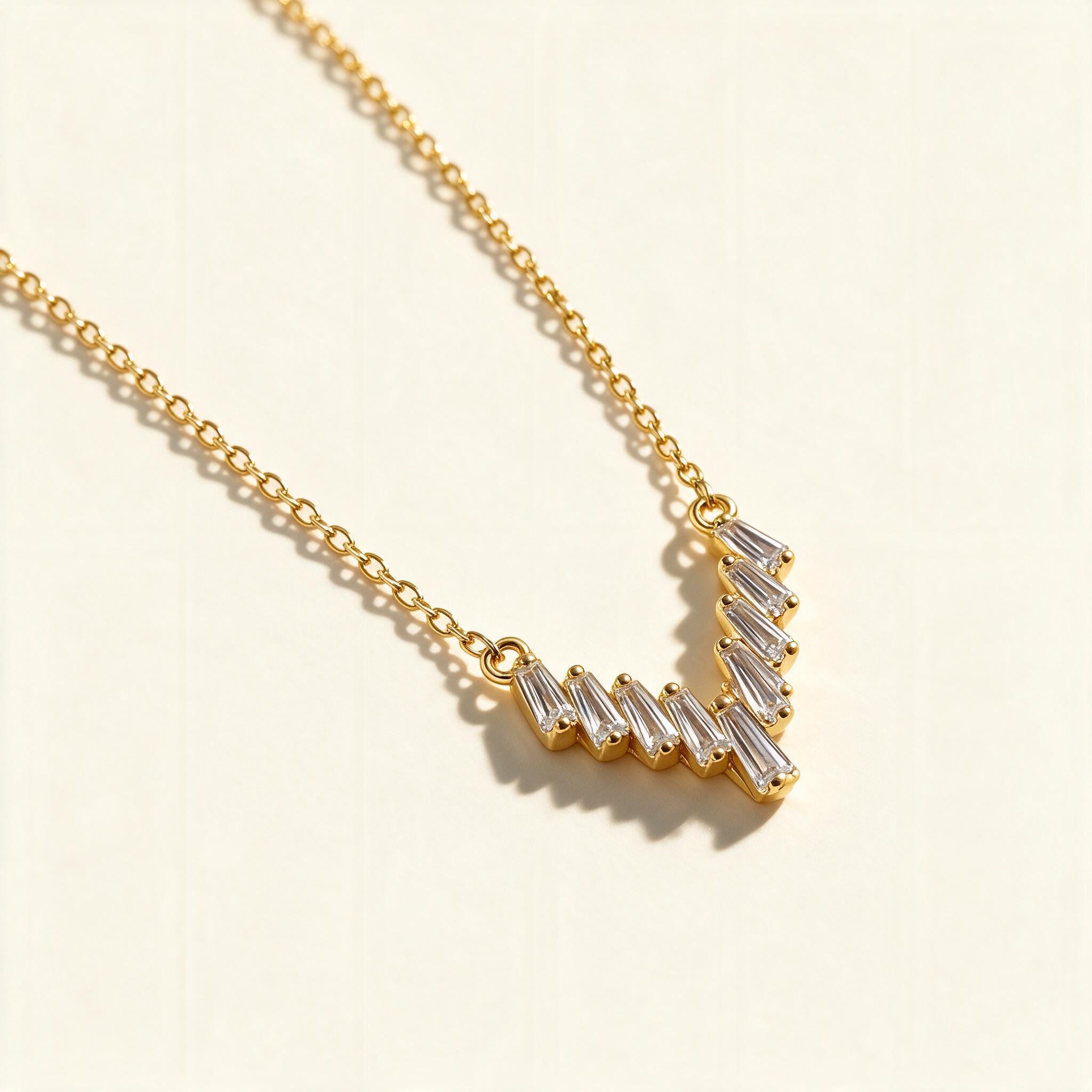 Gold-tone chain necklace with a V-shaped chevron bar of tapered baguette cubic zirconia stones
