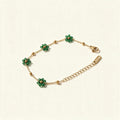 Gold-tone chain bracelet with green floral beads on ivory background