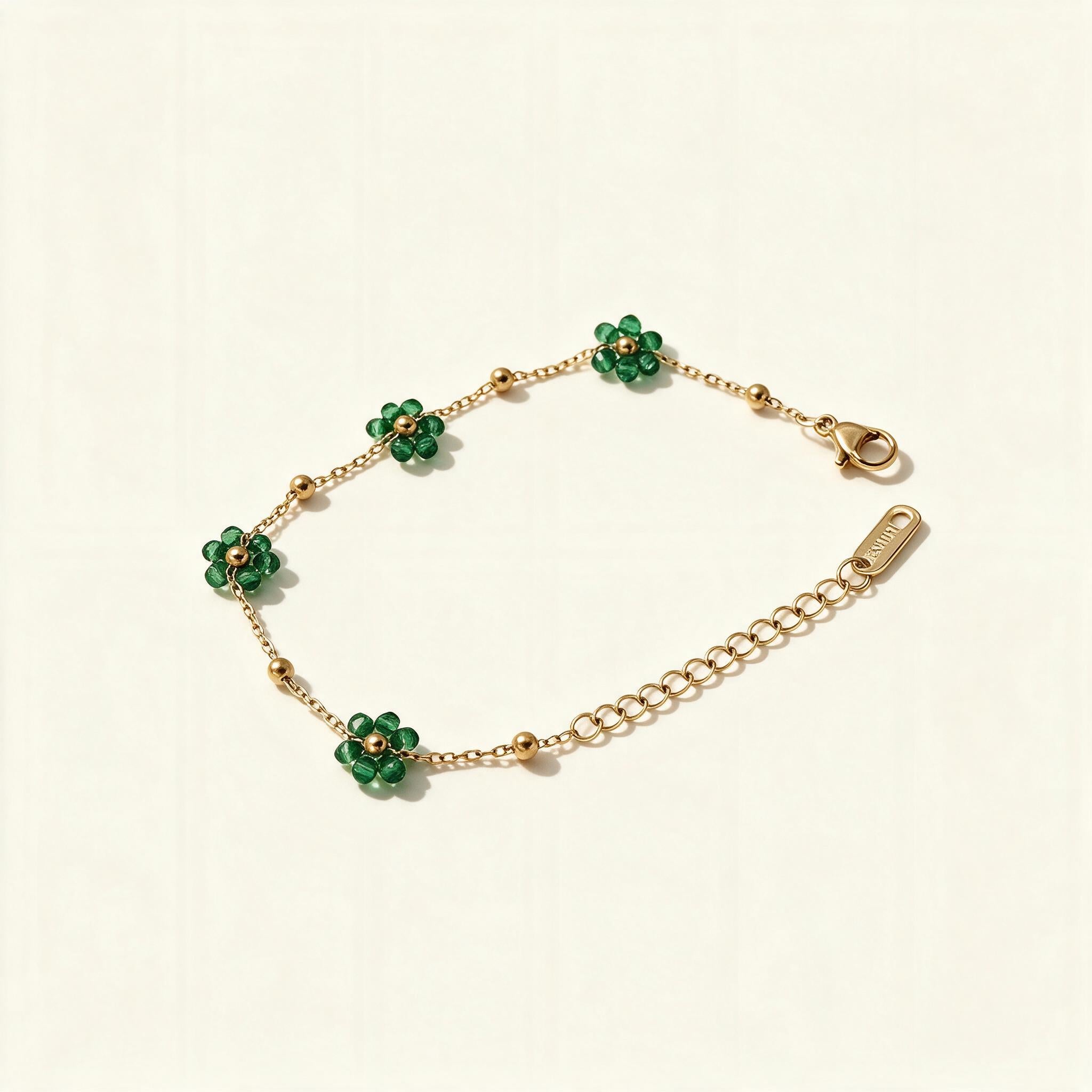 Gold-tone chain bracelet with green floral beads on ivory background