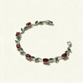 Silver-tone tennis bracelet with red ruby stones and green marquise leaf accents