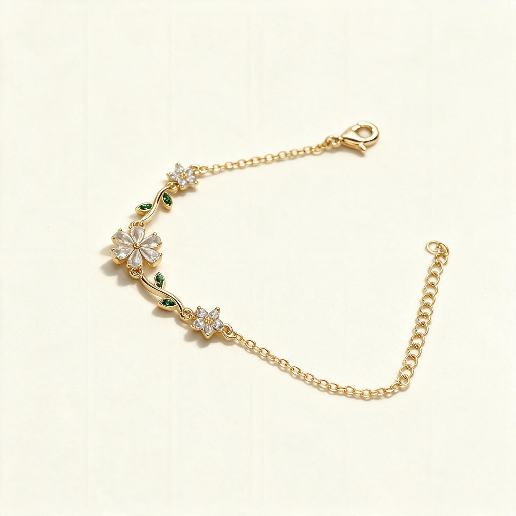 Gold-tone fine chain bracelet with crystal flower and green leaf accents