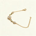 Gold-tone fine chain bracelet with crystal flower and green leaf accents