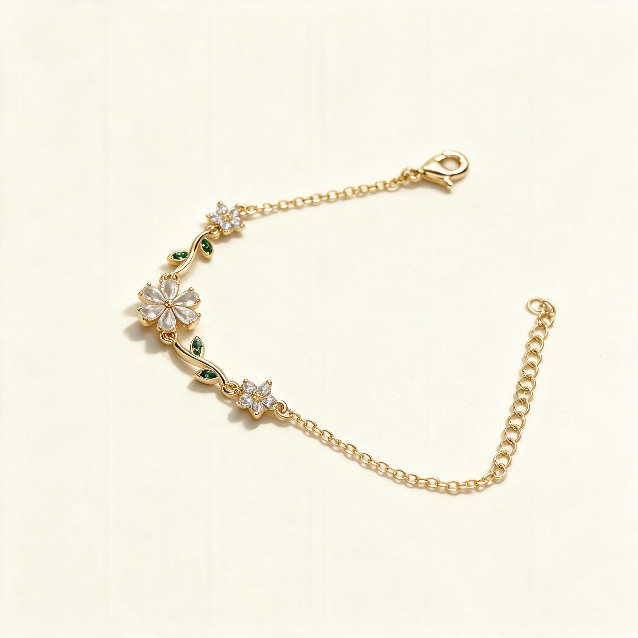 Gold-tone fine chain bracelet with crystal flower and green leaf accents