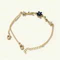 Gold-tone chain bracelet with navy blue enamel flower and green leaf accents