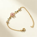 Gold-tone chain bracelet with frosted pink flower and green leaf accents