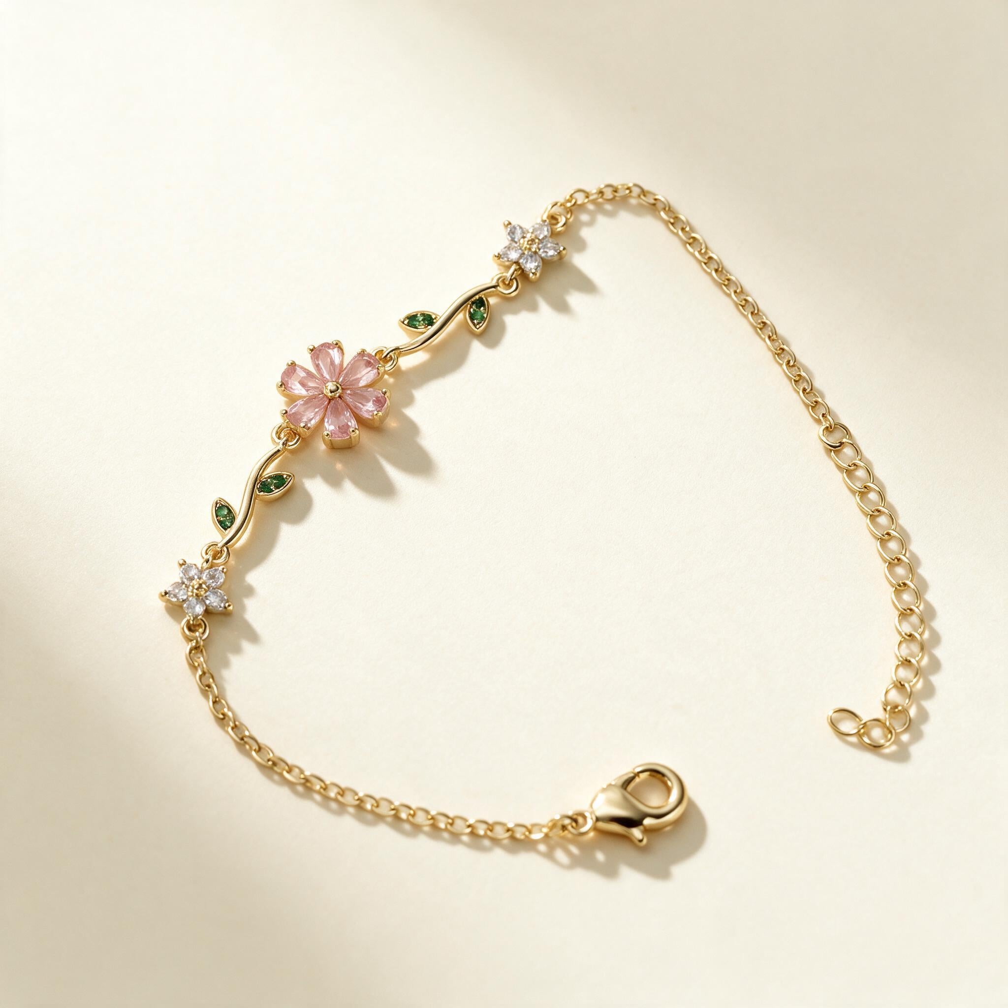 Gold-tone chain bracelet with frosted pink flower and green leaf accents
