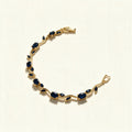 Gold-tone bracelet with sapphire blue oval and marquise stones on a vine design