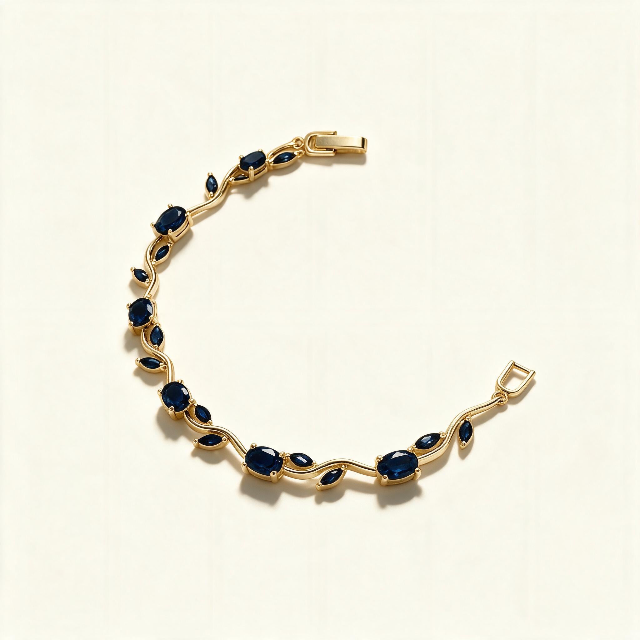 Gold-tone bracelet with sapphire blue oval and marquise stones on a vine design