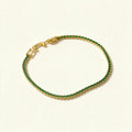 Gold-tone tennis bracelet set with a continuous row of emerald green stones