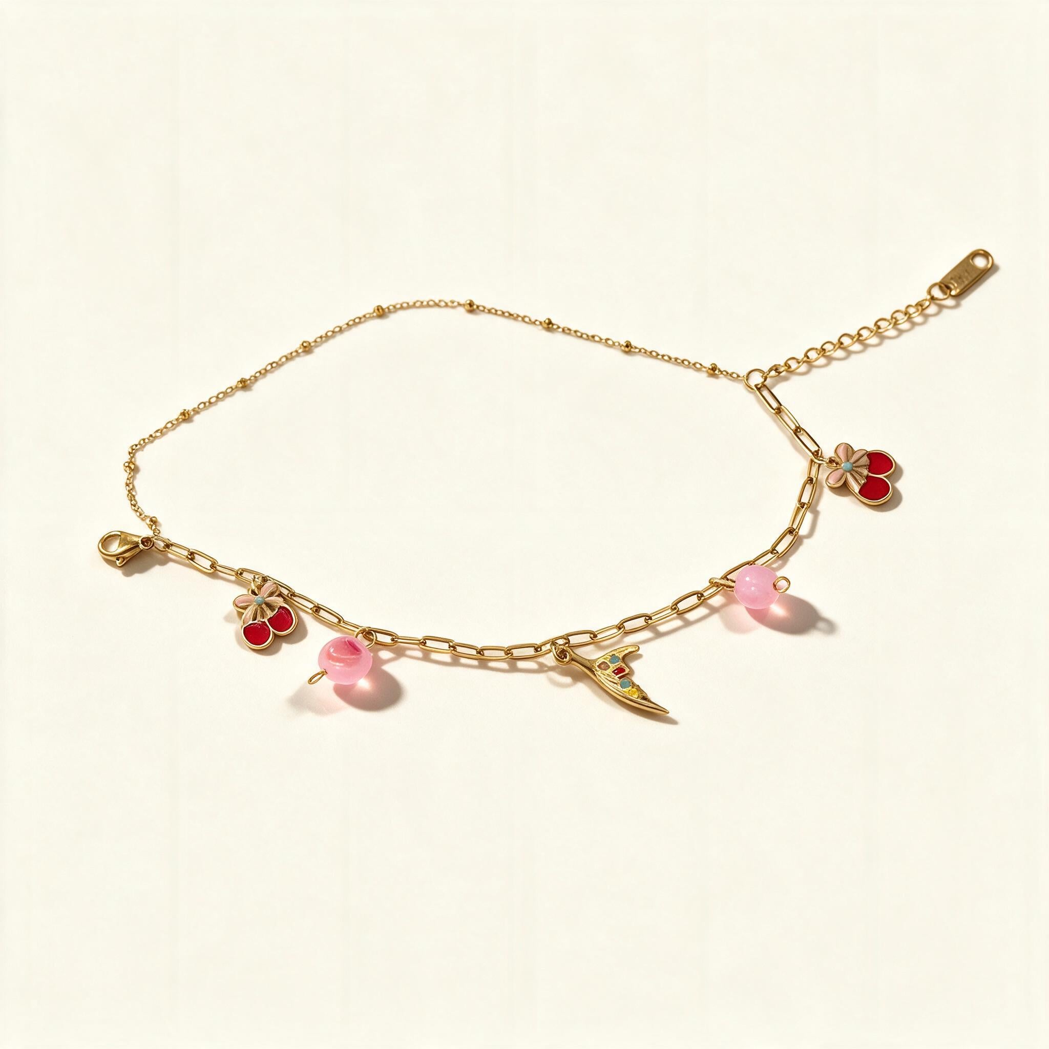 Gold-tone chain bracelet with red enamel cherry charms, daisy and pink beads