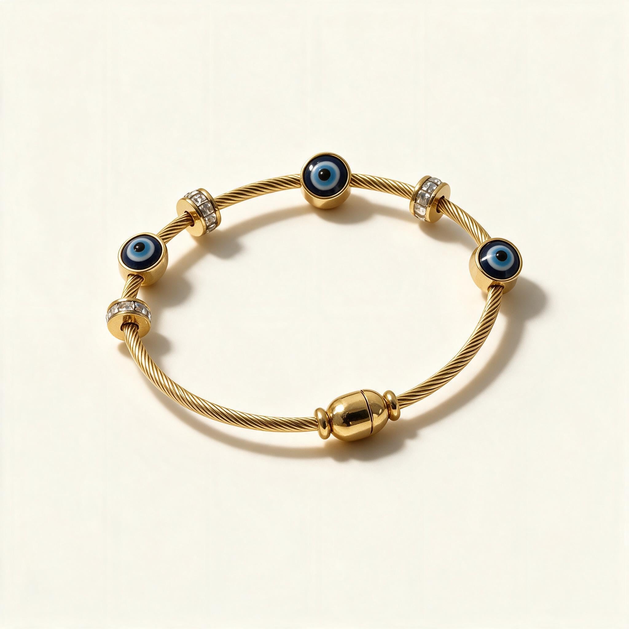 Gold-tone twisted cable bangle with blue evil eye beads and pavé rondelles