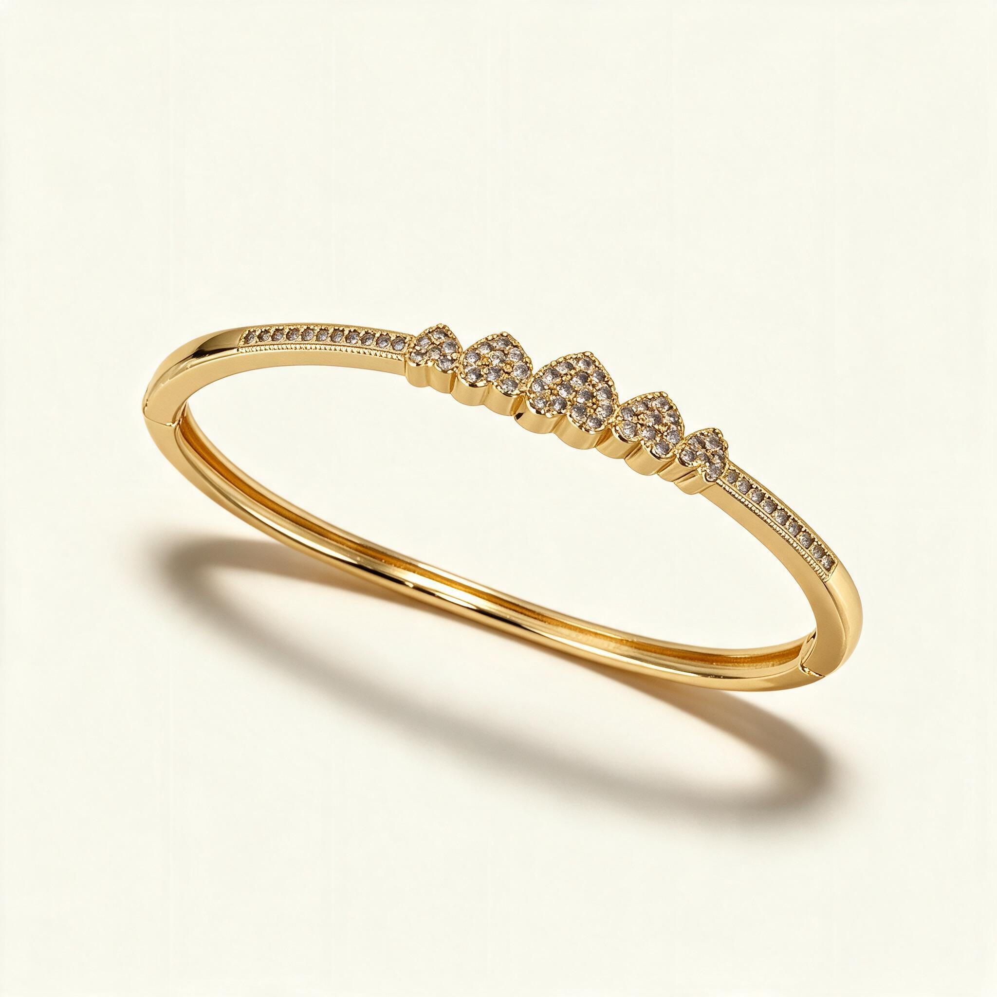 Slim gold-tone bangle with a row of five pavé cubic zirconia hearts