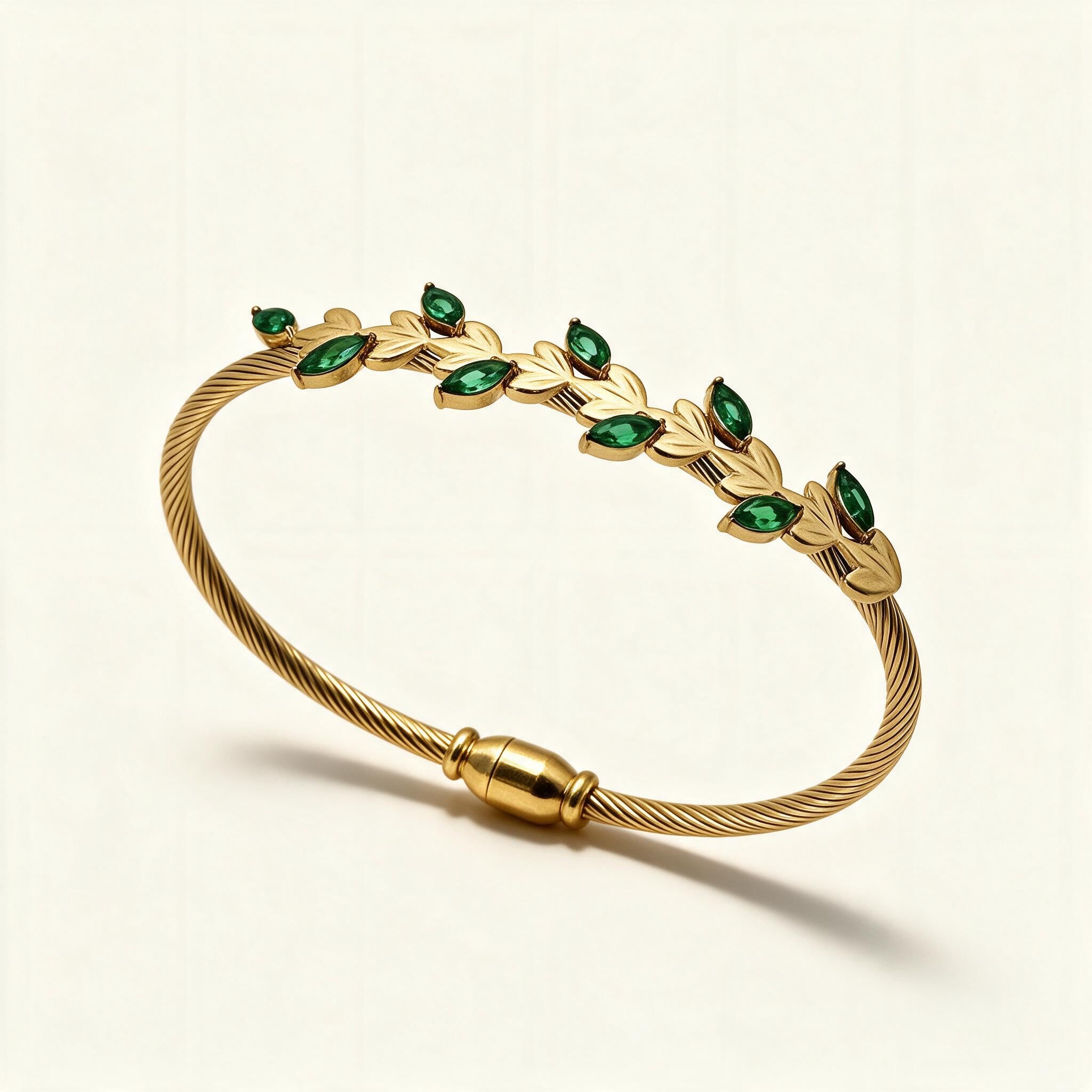 Gold-tone cable bangle with gold leaves and emerald green marquise stones