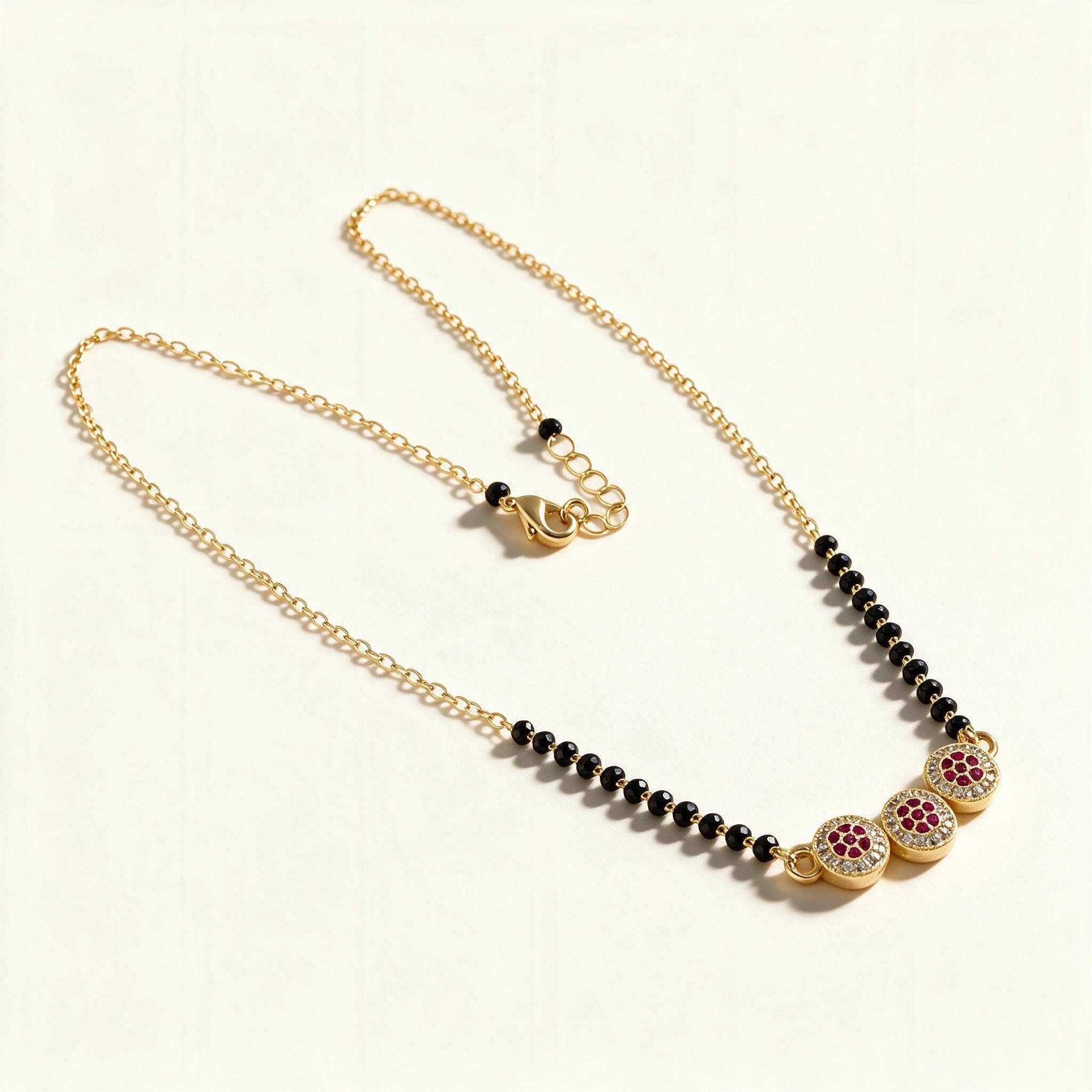 Gold-tone short mangalsutra with black beads and three ruby cubic zirconia discs
