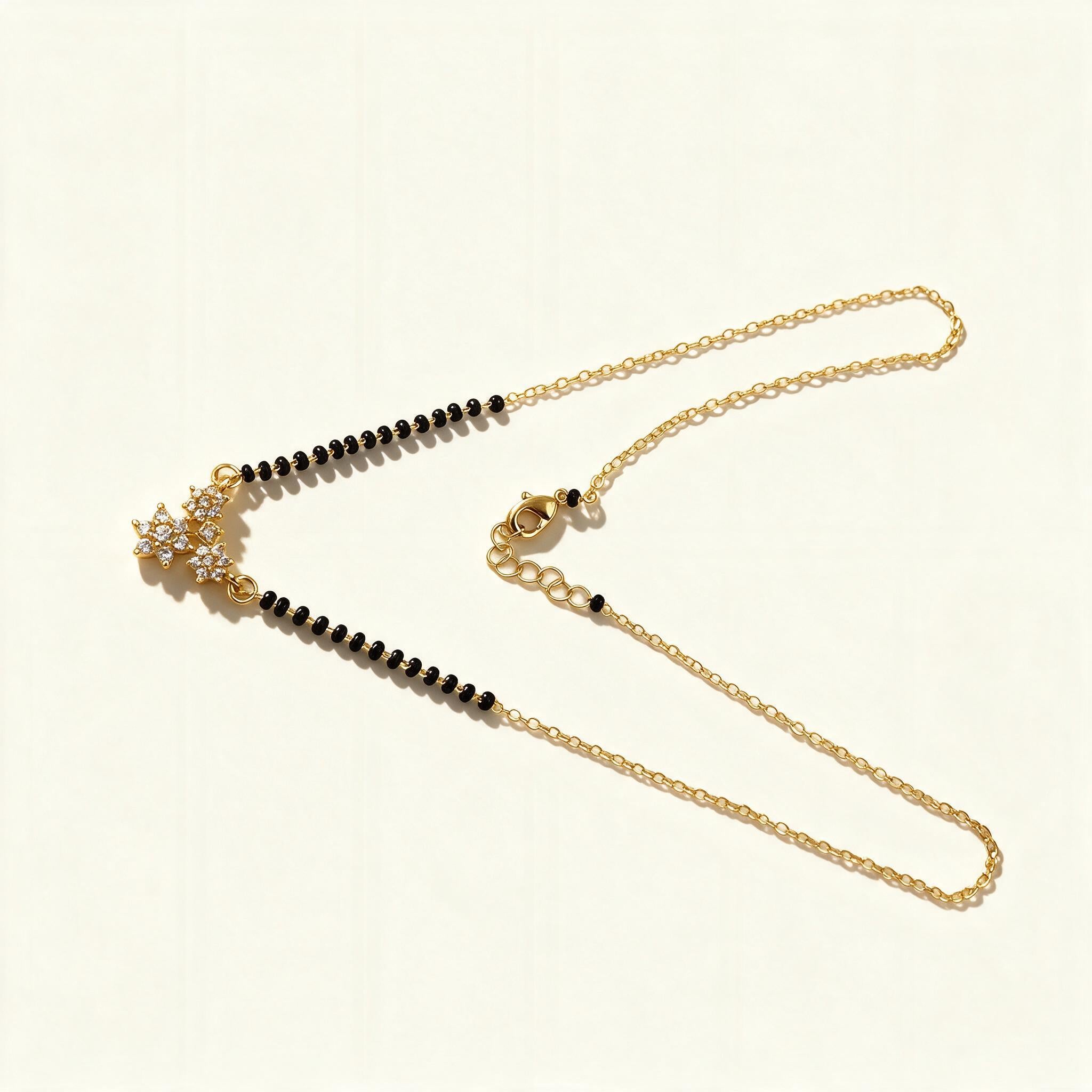 Thin gold-tone mangalsutra with black beads and small cubic zirconia star