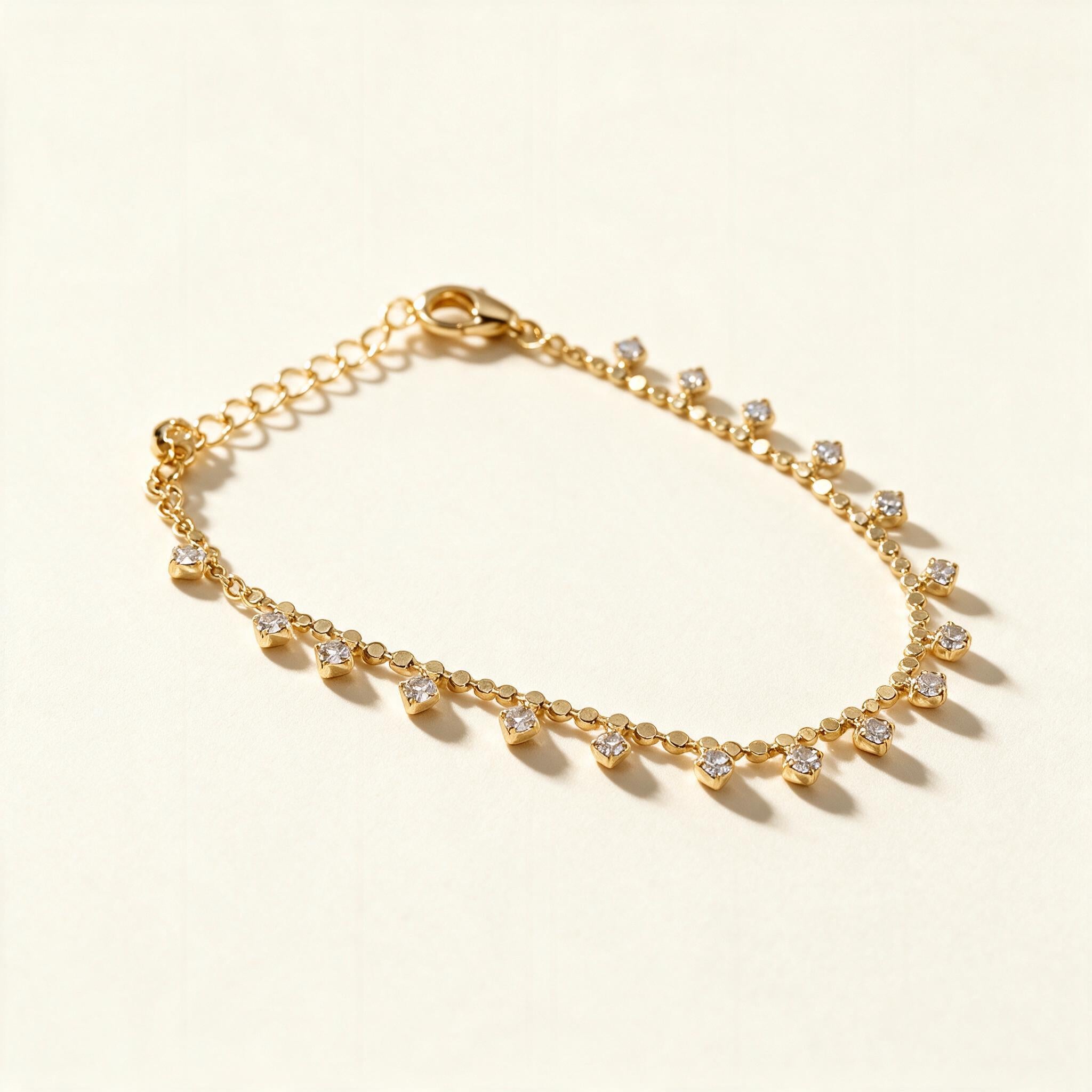 Gold-tone flat disc chain anklet with small hanging cubic zirconia drops on ivory background