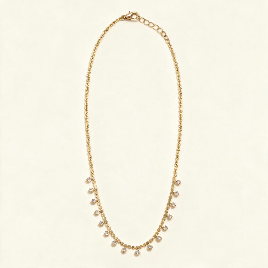 Gold-tone chain necklace with hanging cubic zirconia drops on ivory background