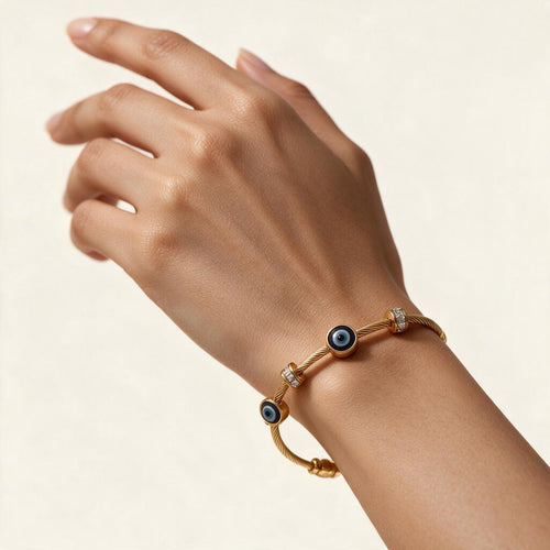 Woman wearing the Amulette gold tone evil eye cable bangle on her wrist