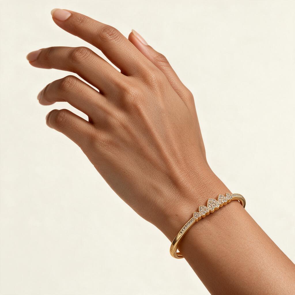 Woman wearing the Coronet gold tone pave heart crown slim bangle on her wrist