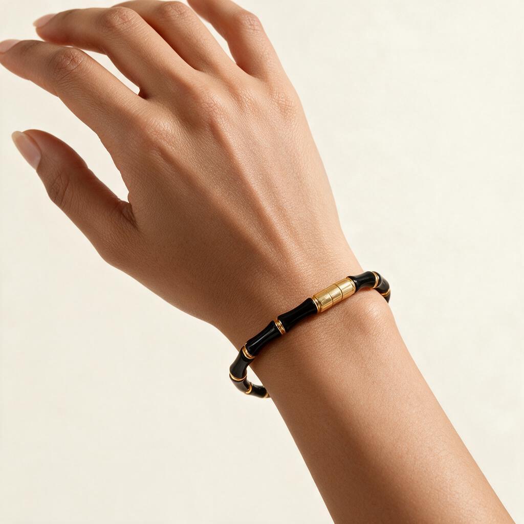 Woman wearing the Camden gold tone black enamel bamboo link slim bangle on her wrist