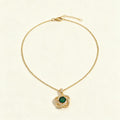 Gold-tone single chain necklace with emerald green knot pendant on ivory background